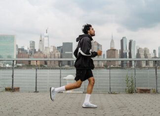 Adult man jogging along a waterfront with the New York City skyline in the background, exuding a vibrant urban lifestyle.
