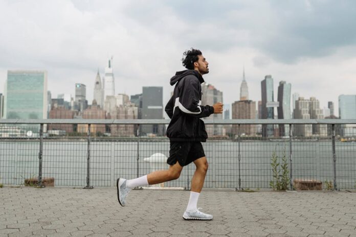 Melhores ténis de corrida masculinos em Portugal: descubra já! Adult man jogging along a waterfront with the New York City skyline in the background, exuding a vibrant urban lifestyle.