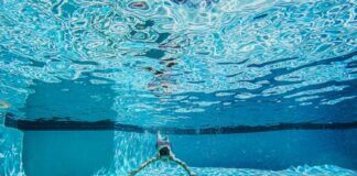 Dynamic underwater view of a person swimming in a clear pool.