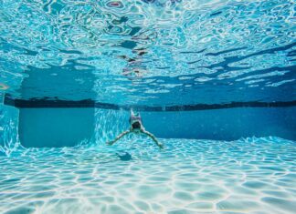 Dynamic underwater view of a person swimming in a clear pool.