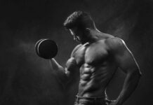 Treino de Crossfit para ganhar força: Descubra o segredo Powerful black and white portrait of a shirtless bodybuilder lifting dumbbells in the gym.