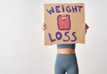 Como emagrecer de forma saudável com exercício: Dicas essenciais Person holding 'weight loss' sign for fitness motivation and health goals.