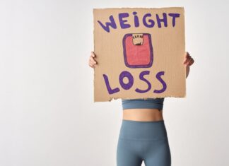 Como emagrecer de forma saudável com exercício: Dicas essenciais Person holding 'weight loss' sign for fitness motivation and health goals.