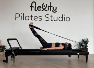 Descubra a melhor roupa para pilates e melhore o seu desempenho Woman performing pilates exercises on a reformer at Flexity Pilates Studio.