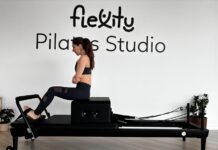 Descubra os benefícios do Pilates Clínico para a sua saúde Focused woman practicing on a Pilates reformer in a modern studio.