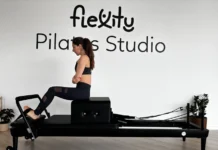 Descubra os benefícios do Pilates Clínico para a sua saúde Focused woman practicing on a Pilates reformer in a modern studio.