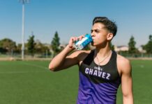 Desporto e qualidade de vida: O segredo para a longevidade Teen athlete hydrating with a sports drink during an outdoor workout.