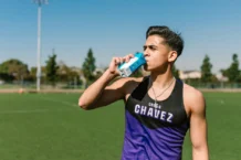 Desporto e qualidade de vida: O segredo para a longevidade Teen athlete hydrating with a sports drink during an outdoor workout.