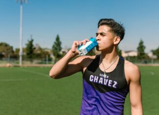 Desporto e qualidade de vida: O segredo para a longevidade Teen athlete hydrating with a sports drink during an outdoor workout.