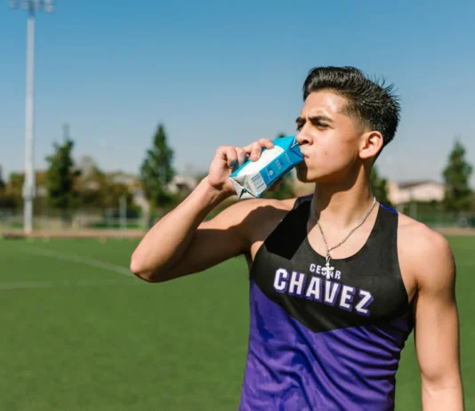 Teen athlete hydrating with a sports drink during an outdoor workout.