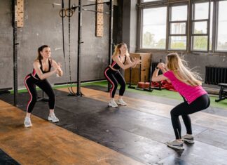 Exercícios para melhorar a postura: Descubra os segredos A group of women exercising inside a gym, performing squats in sportswear.