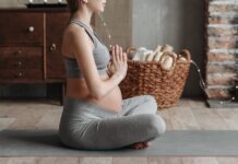 Leggings para grávidas: Conforto e estilo na gravidez Side view of a pregnant woman practicing meditation on a yoga mat indoors, showcasing calm and wellness.