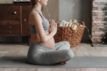Leggings para grávidas: Conforto e estilo na gravidez Side view of a pregnant woman practicing meditation on a yoga mat indoors, showcasing calm and wellness.
