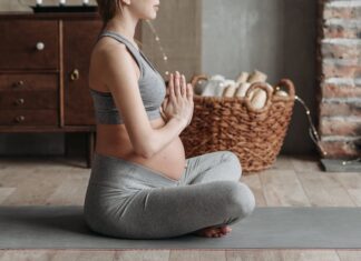 Leggings para grávidas: Conforto e estilo na gravidez Side view of a pregnant woman practicing meditation on a yoga mat indoors, showcasing calm and wellness.