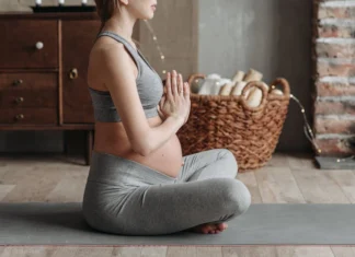 Leggings para grávidas: Conforto e estilo na gravidez Side view of a pregnant woman practicing meditation on a yoga mat indoors, showcasing calm and wellness.