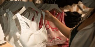 Sutiã desportivo: O segredo para conforto e performance A person wearing a face mask shops for sports bras in a retail store.