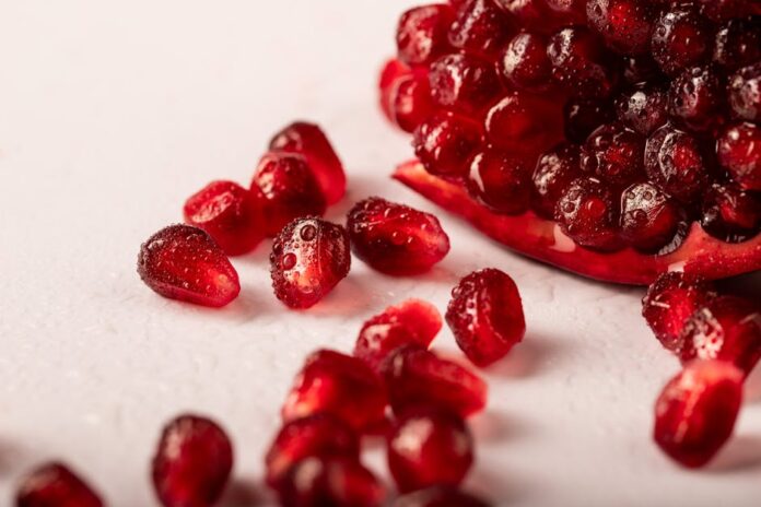 Vida Saudável: 7 Segredos que Transformam Seu Dia a Dia Vibrant close-up of juicy pomegranate seeds with droplets, ideal for healthy food concepts.