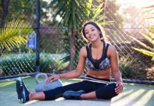 Atividades físicas gratuitas ao ar livre Young woman relaxing after a workout in a sunny outdoor park setting.