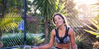 Young woman relaxing after a workout in a sunny outdoor park setting.