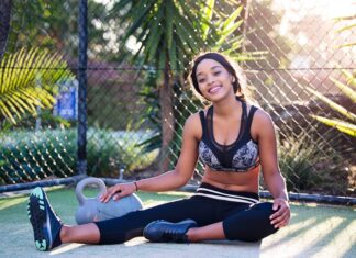 Young woman relaxing after a workout in a sunny outdoor park setting.