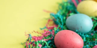 Atividades físicas para fazer na Páscoa: Inove o seu feriado Vibrant Easter eggs lying on colorful shredded paper, perfect for spring celebrations.