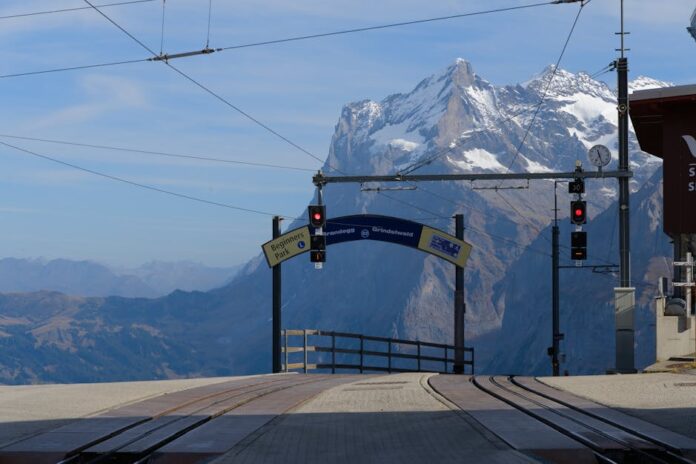 Caminhadas na montanha: 7 dicas essenciais para iniciantes Scenic view of train station with Swiss Alps in the background. Perfect for travel enthusiasts.