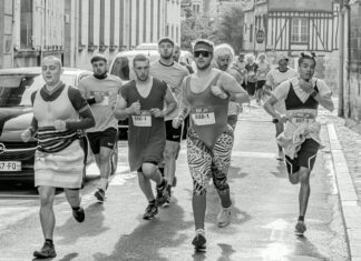 Participants in a fun run wearing various costumes on a city street. Energetic race scene.