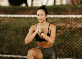 Os benefícios do treino funcional ao ar livre Woman doing squats in a park, embracing fitness and healthy lifestyle.