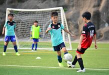 Desporto para Crianças: Atividades incríveis nas férias Boys playing soccer during a team training session outdoors on a sunny day.