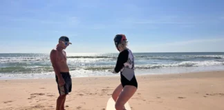 Desporto para séniores iniciantes: Dicas surpreendentes A woman learning to surf with an instructor on a sunny beach day.