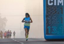 Meia Maratona: Dicas exclusivas e segredos Focused runner at California International Marathon with distance marker in soft light.