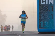 Meia Maratona: Dicas exclusivas e segredos Focused runner at California International Marathon with distance marker in soft light.