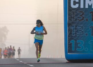 Focused runner at California International Marathon with distance marker in soft light.