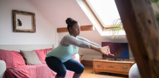 Personal Trainer ao domicílio A woman performs squats on a yoga mat in a cozy living room, promoting home fitness and wellness.