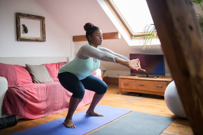 Personal Trainer ao Domicílio: Preço Surpreendente Aqui! A woman performs squats on a yoga mat in a cozy living room, promoting home fitness and wellness.