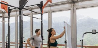 A gym coach instructs on whiteboard beside fitness equipment with mountain view.