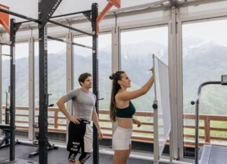 A gym coach instructs on whiteboard beside fitness equipment with mountain view.