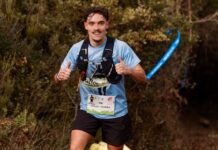 Provas de Trail Running: Descubra as rotas mais desafiadoras Young male trail runner enthusiastically giving a thumbs up during an outdoor race through forest.