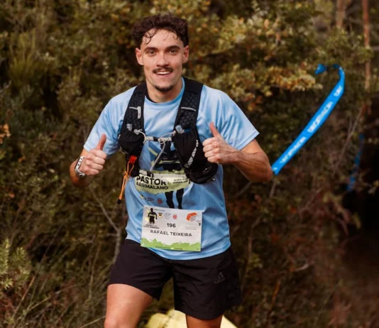 Provas de Trail Running: Descubra as rotas mais desafiadoras Young male trail runner enthusiastically giving a thumbs up during an outdoor race through forest.