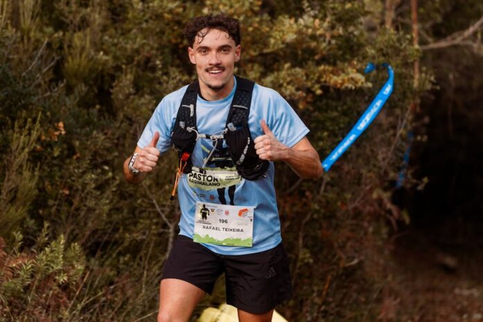 Provas de Trail Running: Descubra as Rotas Mais Desafiadoras Young male trail runner enthusiastically giving a thumbs up during an outdoor race through forest.