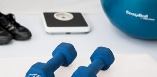 Blue dumbbells placed on a white surface with fitness equipment in the background.