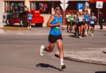Treino para a São Silvestre: Dicas essenciais Dynamic image of a male athlete leading a marathon on a sunny day, showcasing determination and endurance.