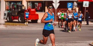 Treino para a São Silvestre: Dicas essenciais Dynamic image of a male athlete leading a marathon on a sunny day, showcasing determination and endurance.