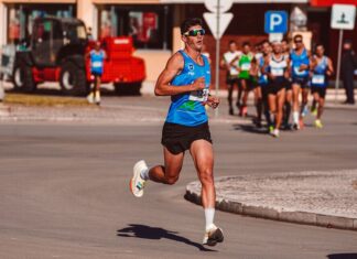 Treino para a São Silvestre: Dicas essenciais Dynamic image of a male athlete leading a marathon on a sunny day, showcasing determination and endurance.