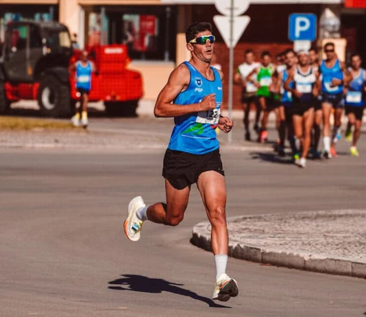 Treino para a São Silvestre: Dicas essenciais Dynamic image of a male athlete leading a marathon on a sunny day, showcasing determination and endurance.